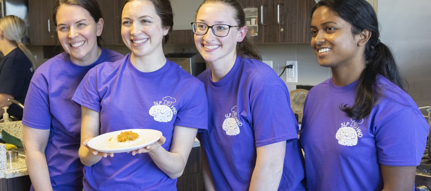 young women standing behind a counter with plates of food on the counter